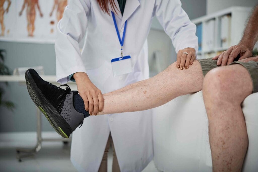 A brightly lit medical examination room, with a central focus on a person's leg extended for a close-up view of the knee joint A brightly lit medical examination room, with a central focus on a person's leg extended for a close-up view of the knee joint