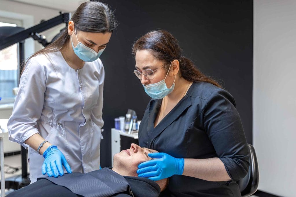 A close-up view of a dermatologist's hand performing a skin biopsy procedure on a patient's face