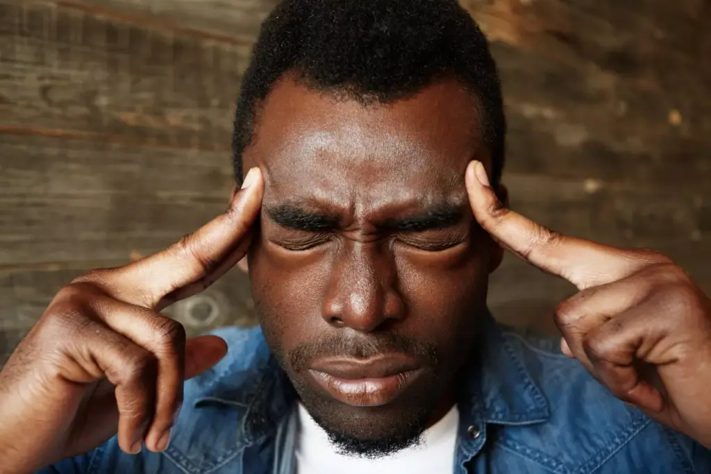 A close-up view of a human head, tilted to one side, with visible signs of distress on the face. The forehead is creased, the eyes are squinting, and the mouth is contorted in a grimace, conveying the intense pain of a persistent headache. The skin appears flushed, and the veins on the temples are visible, pulsing with each throb of the ache. The background is blurred, hazy, and dimly lit, creating a sense of isolation and the individual's sole focus on the debilitating discomfort. The lighting is soft and shadows are cast across the face, adding depth and dimension to the image. The overall composition and mood evoke the anguish and discomfort associated with a brain tumor-induced headache. A close-up view of a human head, tilted to one side, with visible signs of distress on the face. The forehead is creased, the eyes are squinting, and the mouth is contorted in a grimace, conveying the intense pain of a persistent headache. The skin appears flushed, and the veins on the temples are visible, pulsing with each throb of the ache. The background is blurred, hazy, and dimly lit, creating a sense of isolation and the individual's sole focus on the debilitating discomfort. The lighting is soft and shadows are cast across the face, adding depth and dimension to the image. The overall composition and mood evoke the anguish and discomfort associated with a brain tumor-induced headache.