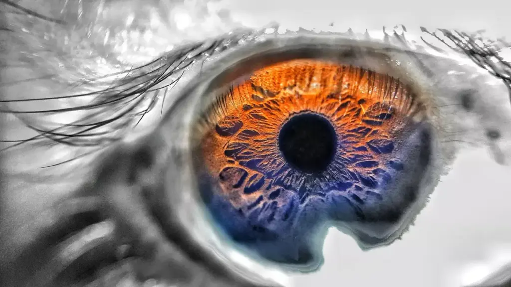 A close-up view of a person's eye, their vision distorted and blurred as if looking through a kaleidoscope. The iris appears enlarged, the pupil dilated, and the sclera tinged with a faint hue of red. The image has a dreamlike, unsettling quality, conveying the disorienting visual experience associated with brain tumor-induced vision changes. Soft, diffused lighting casts an ethereal glow, emphasizing the distortion and discomfort of the subject's altered perception. The background is slightly out of focus, drawing the viewer's attention to the unsettling, yet captivating, focal point of the eye.