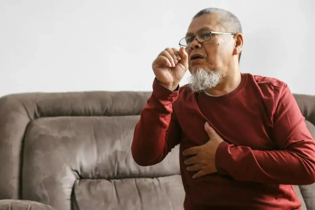 A close-up view of a person's throat, with a focus on the vocal cords and surrounding tissues. The image should clearly depict the characteristic cough associated with atrial fibrillation (AFib), showcasing the raspy, hoarse, and intermittent nature of the cough. The subject's face should be partially visible, with a slight frown or pained expression, conveying the discomfort and irritation caused by the AFib cough. The lighting should be soft and natural, creating a sense of clinical observation, while the depth of field should emphasize the central area of interest. The background should be neutral and uncluttered, allowing the viewer to concentrate on the defining features of the AFib cough.