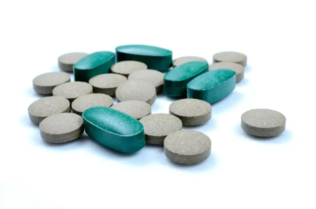 A high-contrast close-up shot of an assortment of chemotherapy drug capsules and tablets against a stark white background. The medications, in various shades of blue, green, and yellow, are arranged with meticulous precision, casting long, dramatic shadows. The lighting is dramatic, with a single, directional source creating a strong sense of depth and volume. The overall mood is one of clinical efficacy and scientific authority, conveying the potent and specialized nature of these cancer-fighting pharmaceuticals.