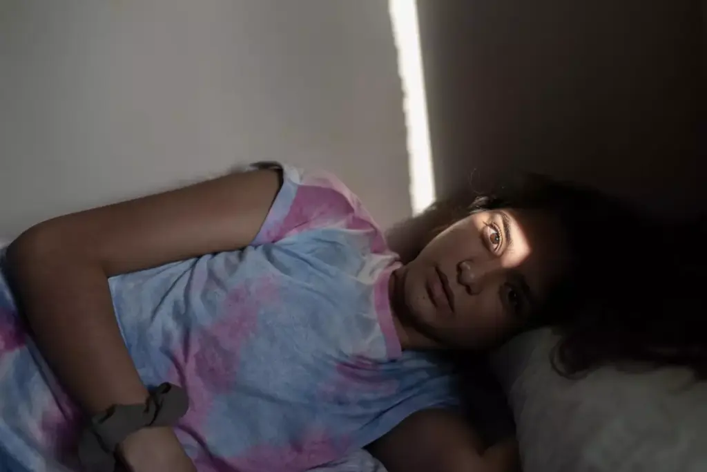 A person lies in bed, their face gaunt and pale from the effects of chemotherapy. Thin wisps of hair cling to their head, a stark contrast to the vibrant life they once held. The room is dimly lit, casting long shadows across the bedsheets, creating a somber and introspective atmosphere. The subject's gaze is distant, conveying the exhaustion and uncertainty of their journey. The scene is captured with a soft, muted color palette, emphasizing the delicate nature of their recovery. A single window in the background allows a sliver of natural light to enter, offering a glimmer of hope amidst the challenges they face. A person lies in bed, their face gaunt and pale from the effects of chemotherapy. Thin wisps of hair cling to their head, a stark contrast to the vibrant life they once held. The room is dimly lit, casting long shadows across the bedsheets, creating a somber and introspective atmosphere. The subject's gaze is distant, conveying the exhaustion and uncertainty of their journey. The scene is captured with a soft, muted color palette, emphasizing the delicate nature of their recovery. A single window in the background allows a sliver of natural light to enter, offering a glimmer of hope amidst the challenges they face.