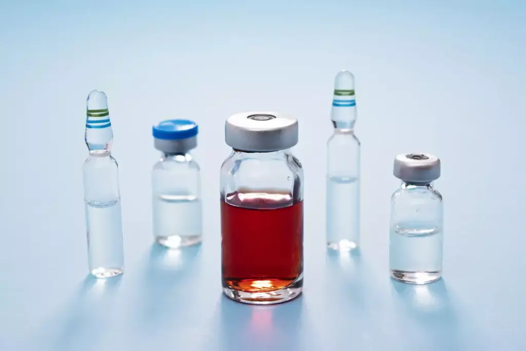 A vibrant array of chemotherapy drugs in glass vials, their liquid contents glowing with a warm, amber hue. The vials are arranged in the foreground, casting dynamic shadows on a sleek, metal laboratory surface. In the middle ground, a microscope and other scientific instruments hint at the precision required to administer these potent medicines. The background is softly blurred, evoking the clinical, high-tech environment of an oncology research lab. Warm, directional lighting accentuates the translucent quality of the vials, conveying a sense of the drugs' potent, yet delicate nature as they target and fight ovarian cancer cells.