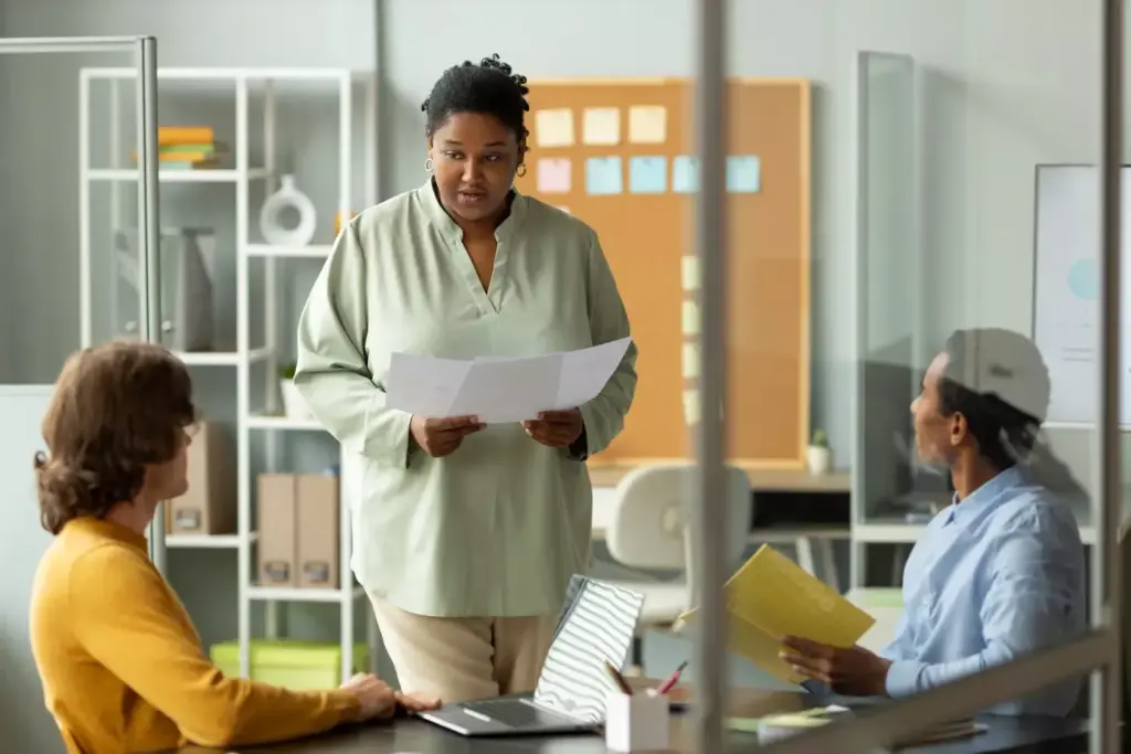 Serene and empowering healthcare setting, soft lighting illuminating a warm, inviting atmosphere. In the foreground, an array of supportive resources - brochures, informational pamphlets, and referral materials neatly organized on a wooden table. In the middle ground, a welcoming nurse or counselor smiling and gesturing towards the resources, conveying a sense of compassionate guidance. The background features soothing, neutral-toned walls, radiating a sense of safety and comfort. The overall scene evokes a comprehensive, patient-centric environment where breast cancer patients and their caregivers can access essential support and information.