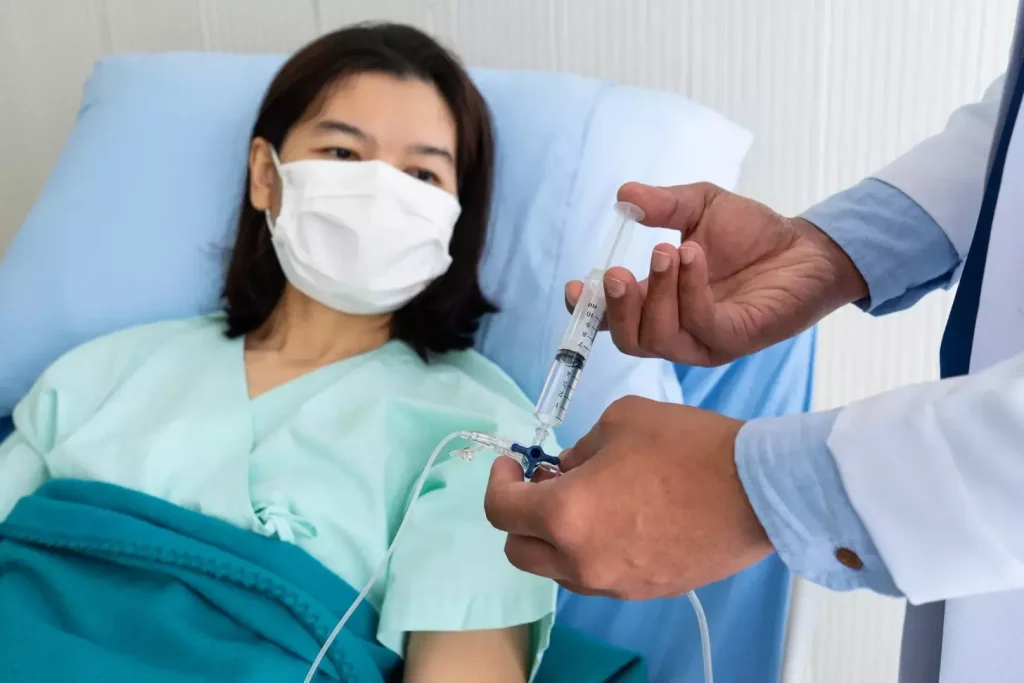 a doctor or nurse in sterile attire holds a syringe filled with a clear liquid, representing the BCG (Bacillus Calmette-Guérin) therapy for bladder cancer. The middle ground features a patient in a reclined position a doctor or nurse in sterile attire holds a syringe filled with a clear liquid, representing the BCG (Bacillus Calmette-Guérin) therapy for bladder cancer. The middle ground features a patient in a reclined position