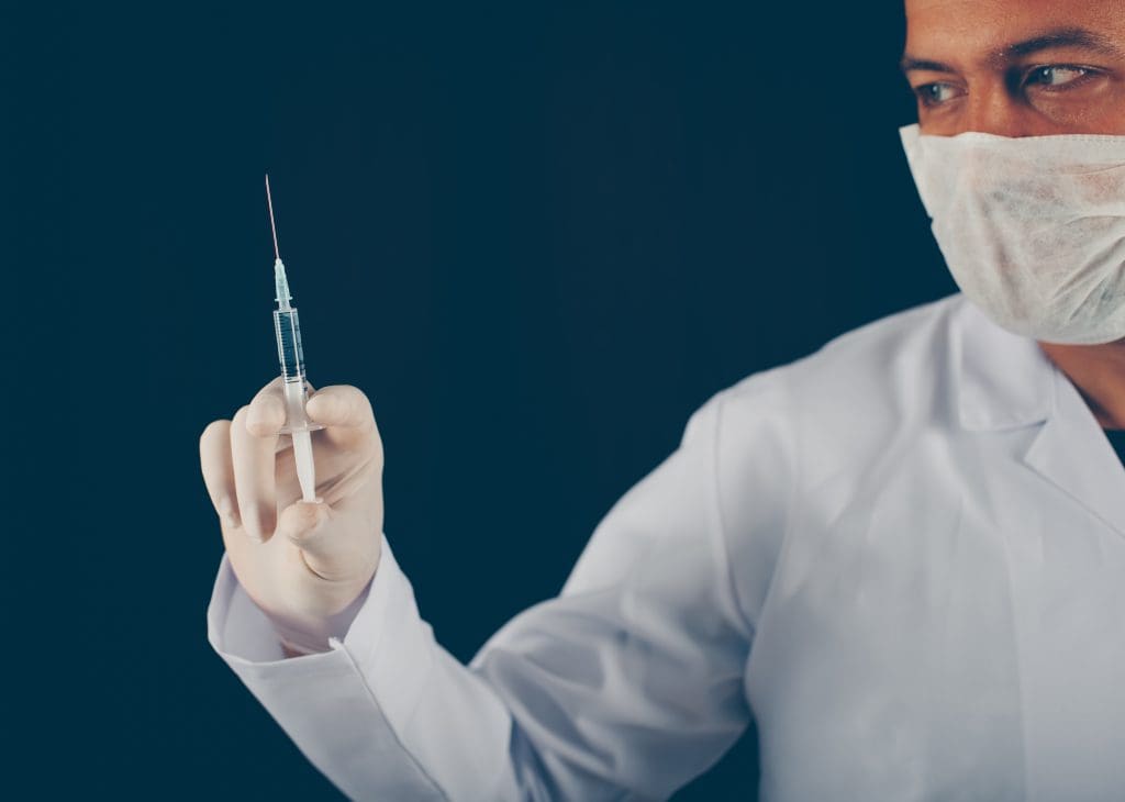 doctor with gloves mask holding syringe his hand side view LIV Hospital