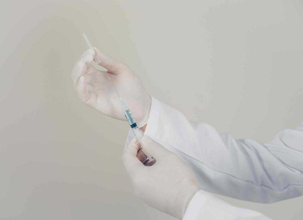 doctor's gloved hands hold a medical syringe filled with bone marrow fluid. doctor's gloved hands hold a medical syringe filled with bone marrow fluid.